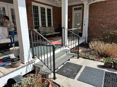 Black stair and landing railings at a covered brick porch