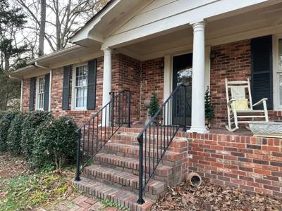 Black stair and porch rails along a brick house with white columns