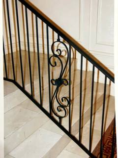 Black stair balustrade with a central scroll panel and wooden handrail