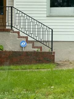 Black stair railing with decorative vertical accents beside white house siding