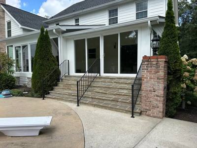 Black stair railings across wide stone steps at a screened porch