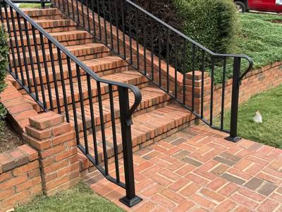 Black stair railings and rounded handrail ends at brick garden steps
