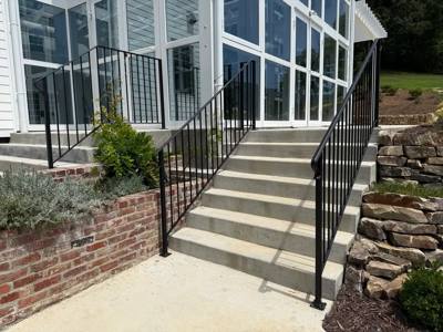 Black stair railings beside a sunroom and brick retaining wall