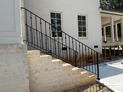 Black stair railings descending beside a white brick porch