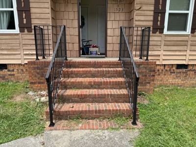 Black stair railings leading up brick steps to a small covered entrance