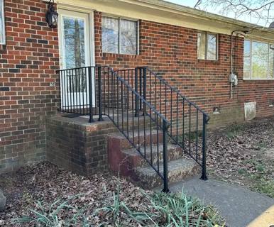 Black stair rails beside a small side entrance on a brick house
