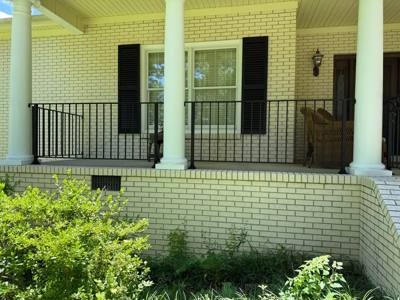 Black vertical-bar railing across a white brick front porch