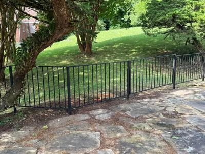 Black vertical-picket fence following a curved stone terrace