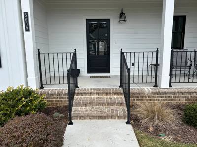 Central brick porch steps framed by black railings and white columns