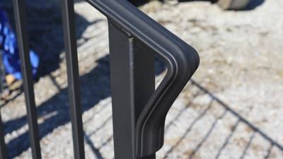 Close-up of a black railing corner with a shaped rounded top rail