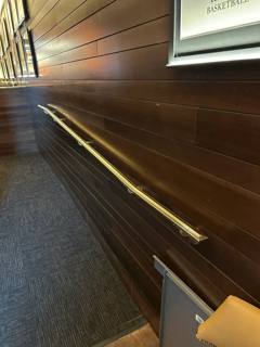 Close view along a wall-mounted handrail in a wood-paneled passage