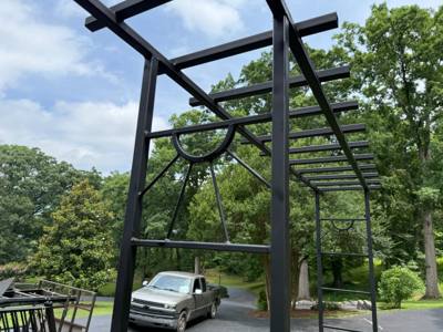 Close view of a black garden arbor with overhead crossbars and side arches