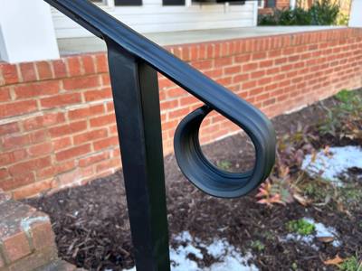 Close view of a black handrail end formed into an open loop