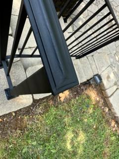 Close view of a black railing post base and broad handrail end