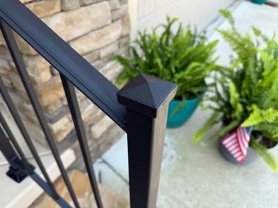 Close view of a black square post cap and sloping railing handrail
