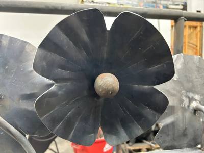 Close view of a dark sculpted metal flower with a round center