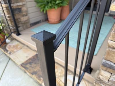Close view of a pyramid-topped railing post and straight black handrail