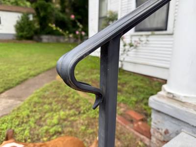 Close view of a rolled black handrail end above a square post