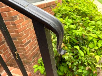 Close view of a rounded black handrail bend beside a brick wall
