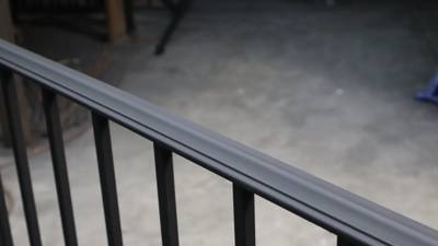 Close view of a smooth black top rail above vertical pickets