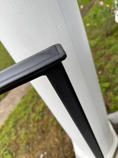 Close view of a straight black handrail end beside a white column