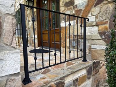 Close view of black railing pickets with decorative collars beside a stone doorway