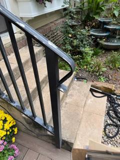 Close view of black stair railing at a garden-side stone landing