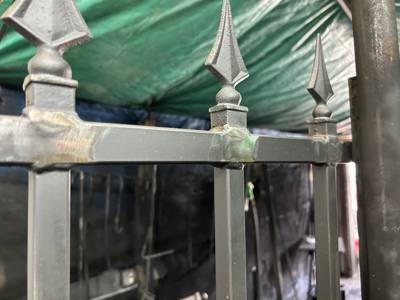 Close view of unpainted spear finials and a decorative fence rail