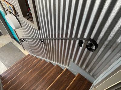 Curled black wall handrail alongside a white beadboard stair wall