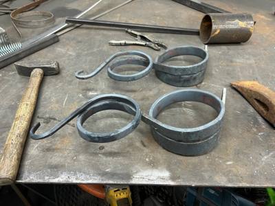 Curled metal scroll components and fabrication tools on a workbench