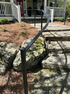 Curved black handrail beside a stone garden stairway