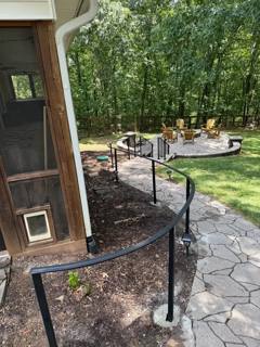 Curved black railing along a stone path around a porch corner