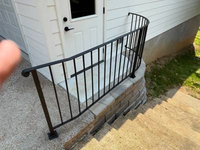 Curved black railing around a small raised landing at a white door