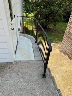 Curved black railing following a rounded concrete entrance landing