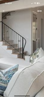 Curved black railing following a white interior staircase