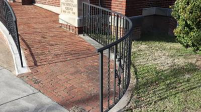 Curved black railing following the edge of a brick entrance path