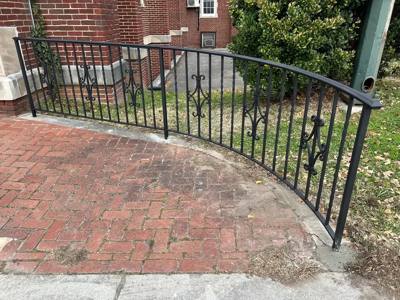 Curved black railing with scroll accents bordering a brick terrace