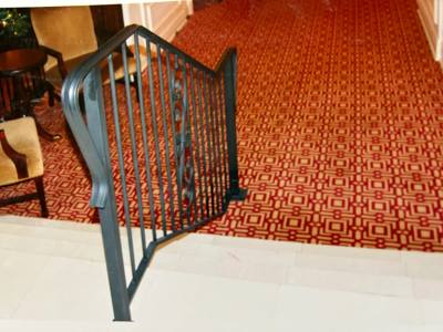 Curved black stair railing wrapping around a carpeted interior landing
