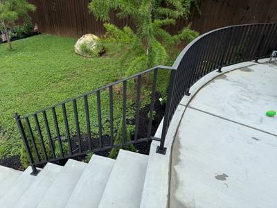 Curved black stair railings following a rounded concrete landing