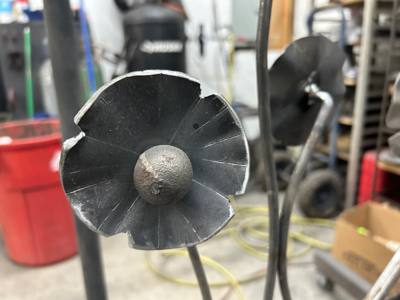Dark metal flower blossom with a rounded center and curled petal edges