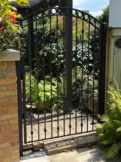 Decorative arched black pedestrian gate between stone pillars