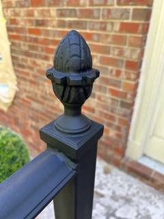 Decorative black acorn-shaped finial atop a square railing post