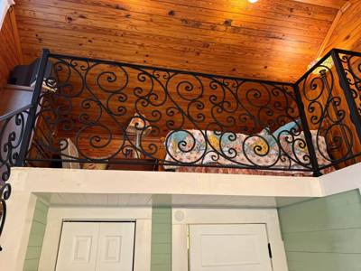 Decorative black landing railing beneath a wood-paneled ceiling