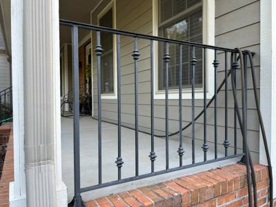 Decorative black railing panel between a porch column and siding