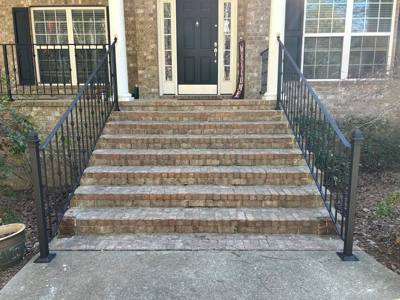 Decorative black railings on broad pale brick entrance steps