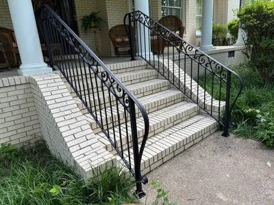 Decorative black railings on white brick porch steps