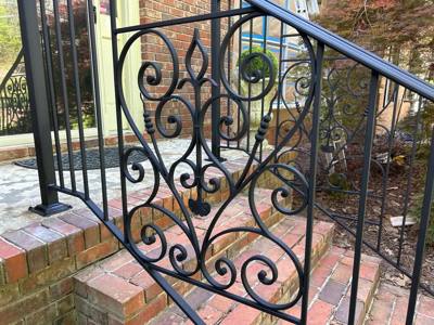 Decorative black scrollwork panel beside brick porch steps