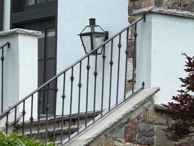 Decorative black stair railing mounted above a stone entrance wall