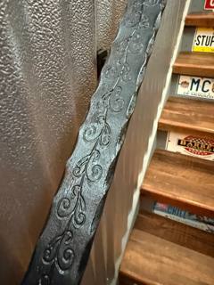Decorative scroll-pattern handrail alongside an interior wooden staircase