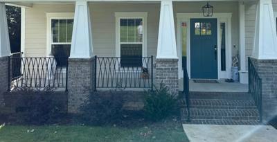 Diamond-pattern porch railing and central steps viewed from the lawn